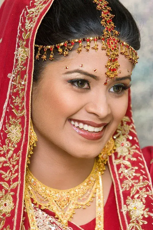 Smiling bride in red bridal attire with traditional jewelry and makeup